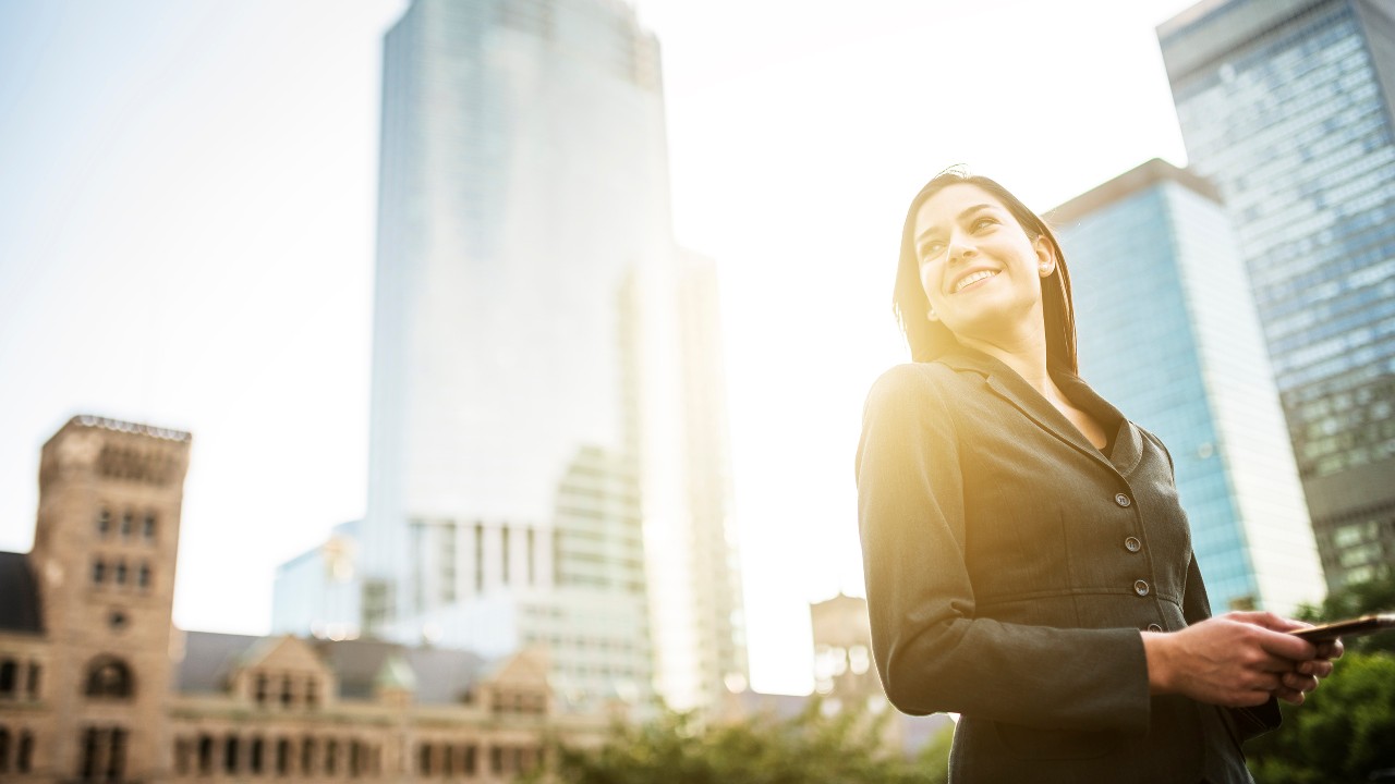 Business woman is holding her phone with a smile; imaged used for HSBC Taiwan foreign exchange page.