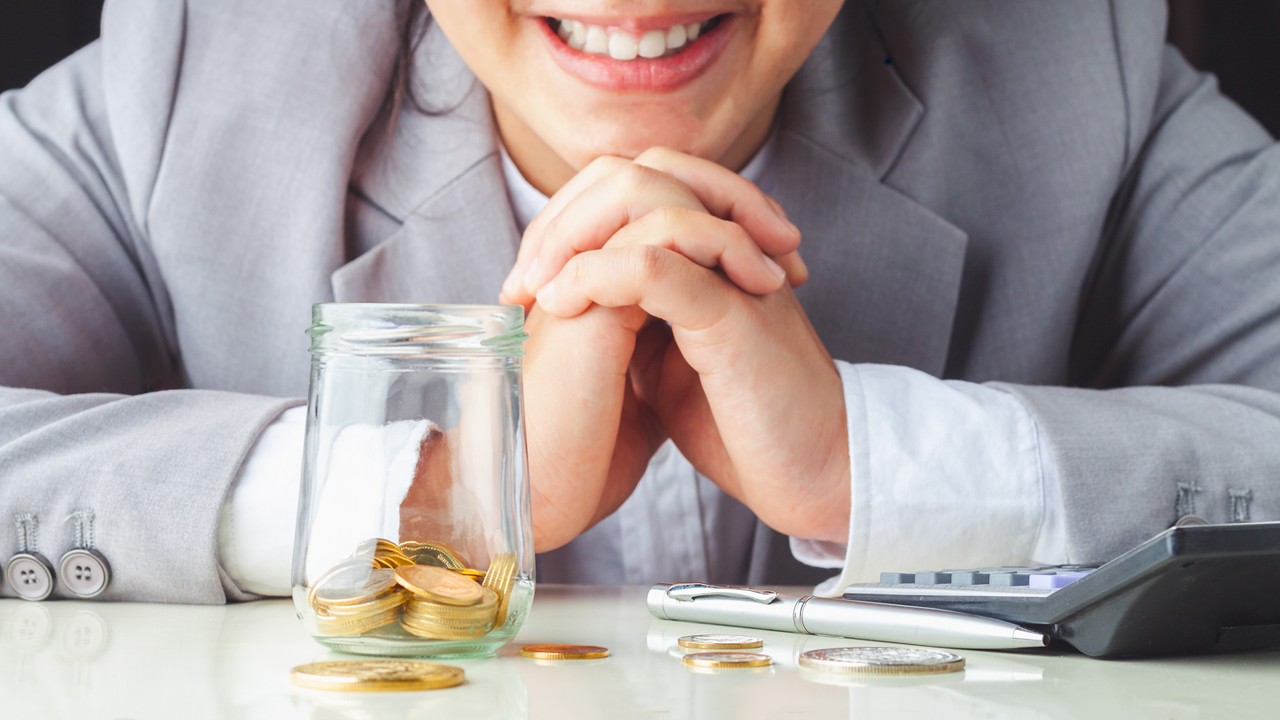 Businessman is smiling at the coins on the table; image used for HSBC Taiwan i-invest for online trading page.