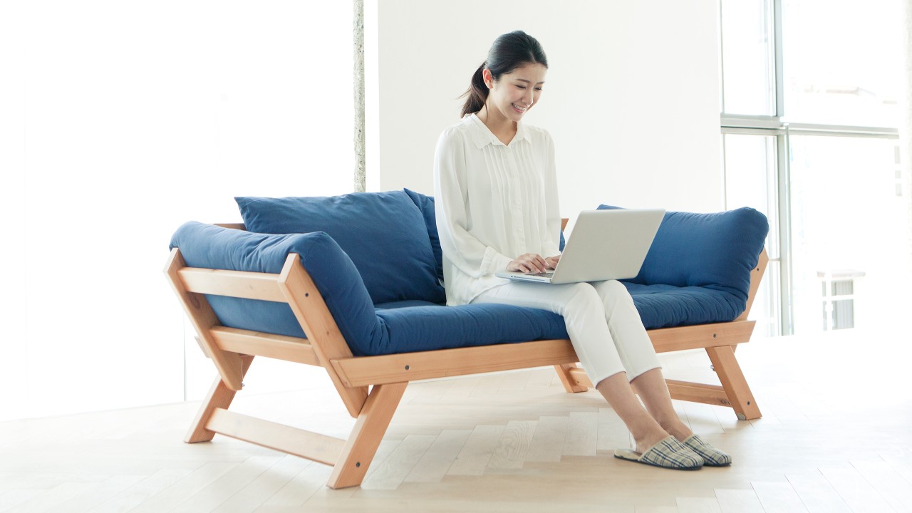 A beautiful lady is looking at a laptop on a sofa;image used for HSBC online banking.