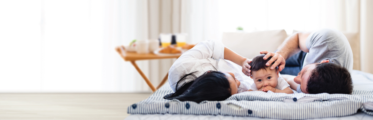 A family of three is lying comfortably in bed; image used for HSBC mortgages page.