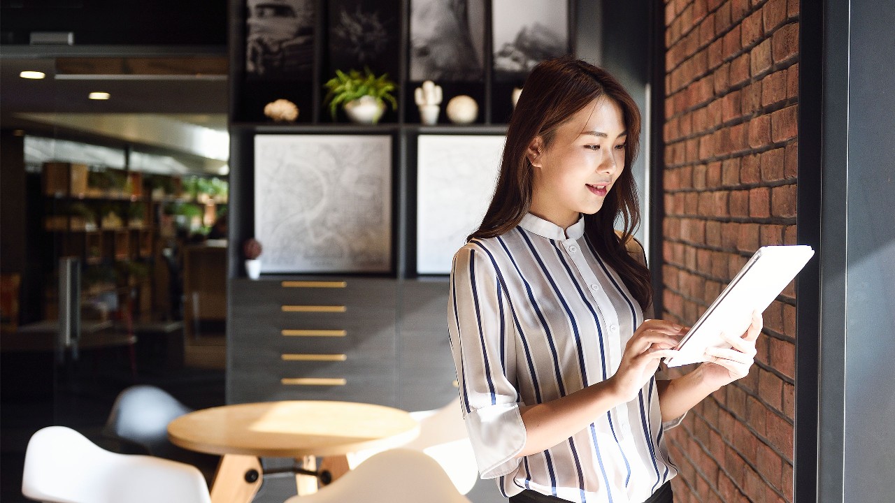 A lady is using tablet next to the window; image used for Offshore bonds.