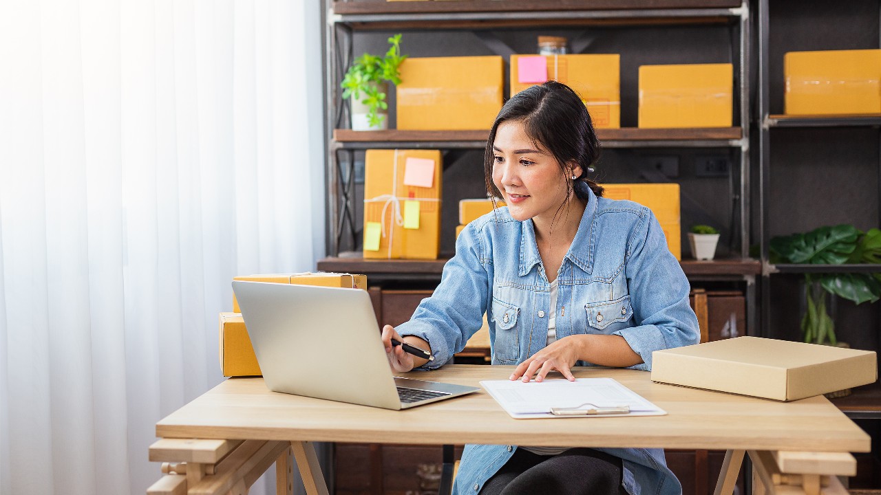  A lady is using a laptop and filling out documents; image used for Exchange Traded Funds (ETF).