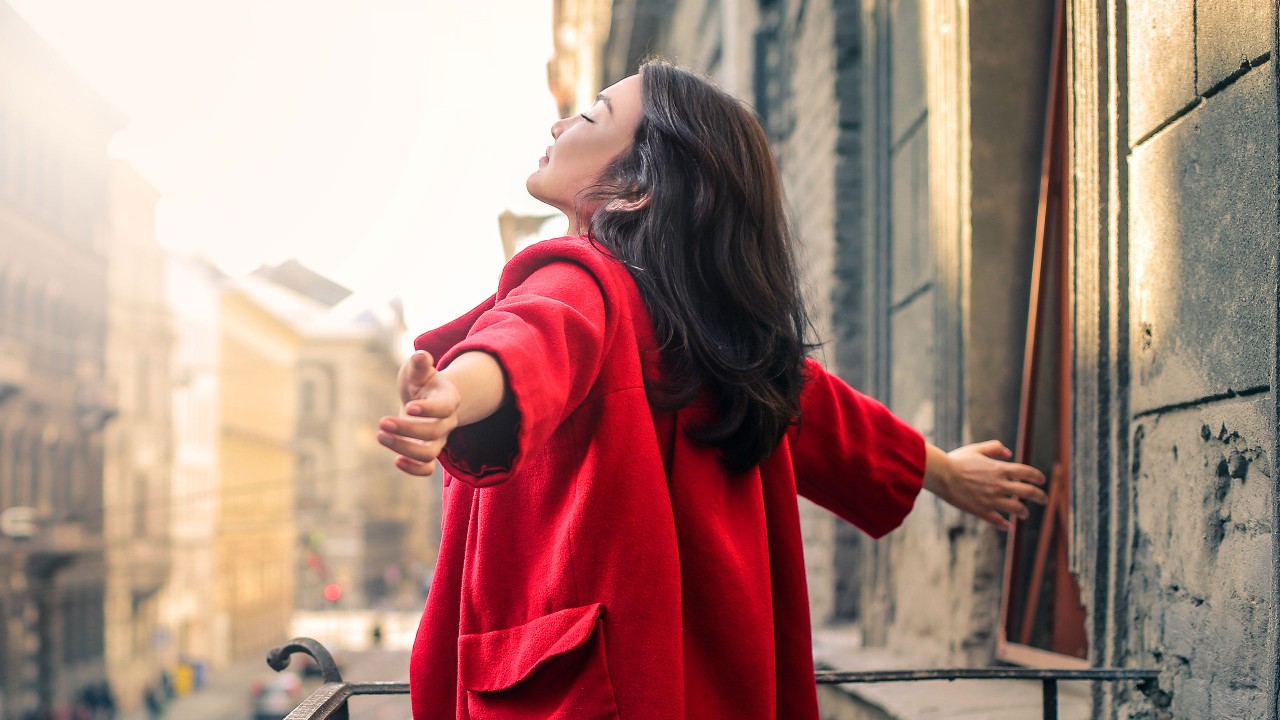 一個女人正在街上擁抱夕陽; 圖片使用於滙豐ACH自動轉帳存入服務活動頁面。